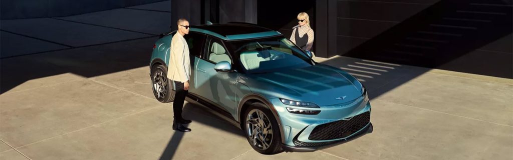 A GV60 Car parked in a garage, with a man and woman standing beside it.