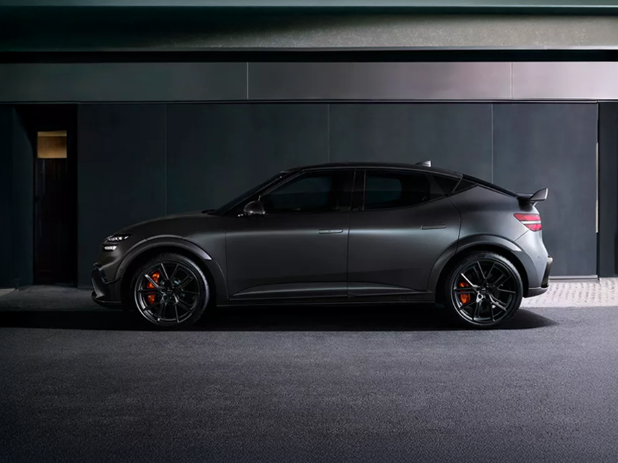 A sleek, modern Genesis car in a matte gray finish, parked in a stylish, dimly lit environment with a minimalist backdrop.