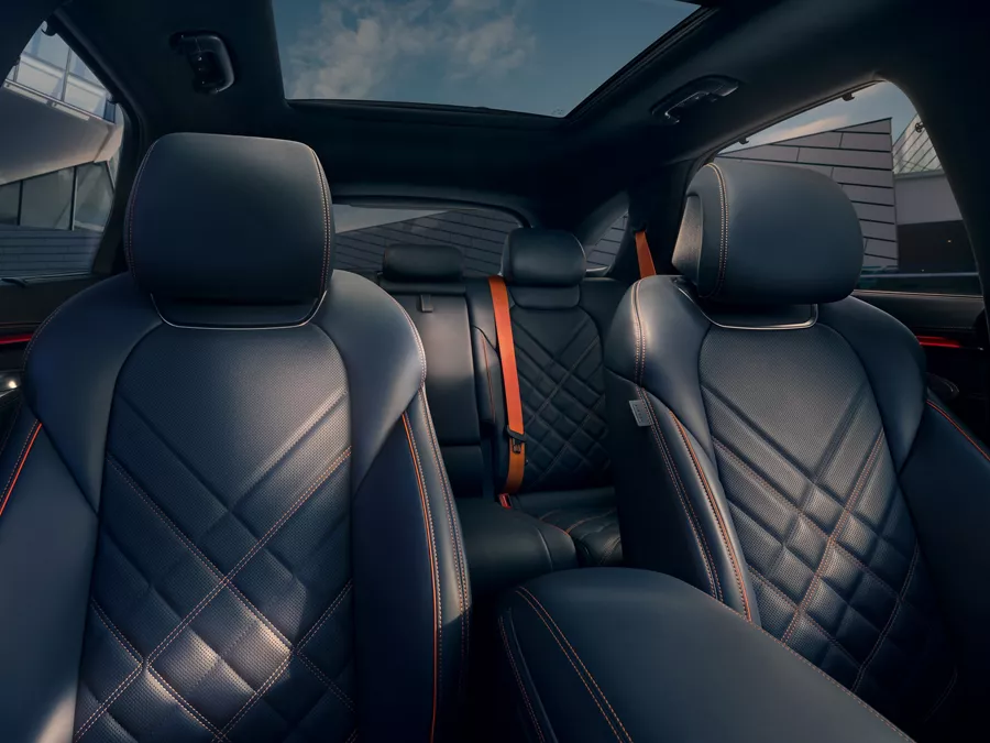 Interior of a Genesis GV70 car featuring leather seats with a diamond pattern and visible seat belts.