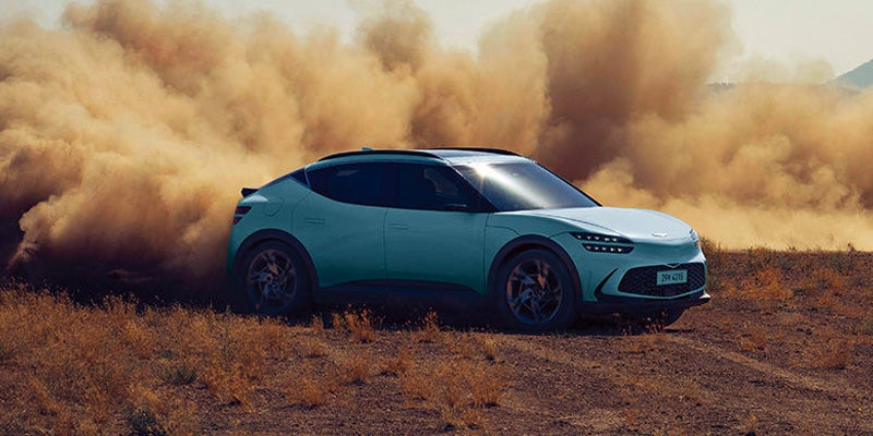 A stylish SUV Genesis GV60 running is dusty road.