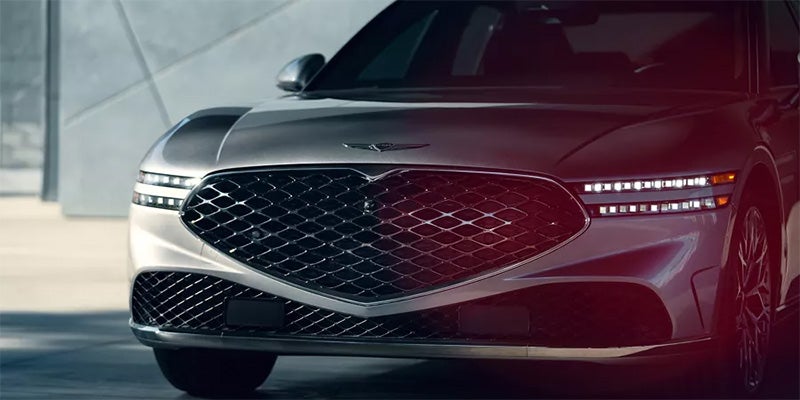 A close-up of Genesis G90 luxury sedan’s front, showcasing its large mesh grille and sleek LED headlights.