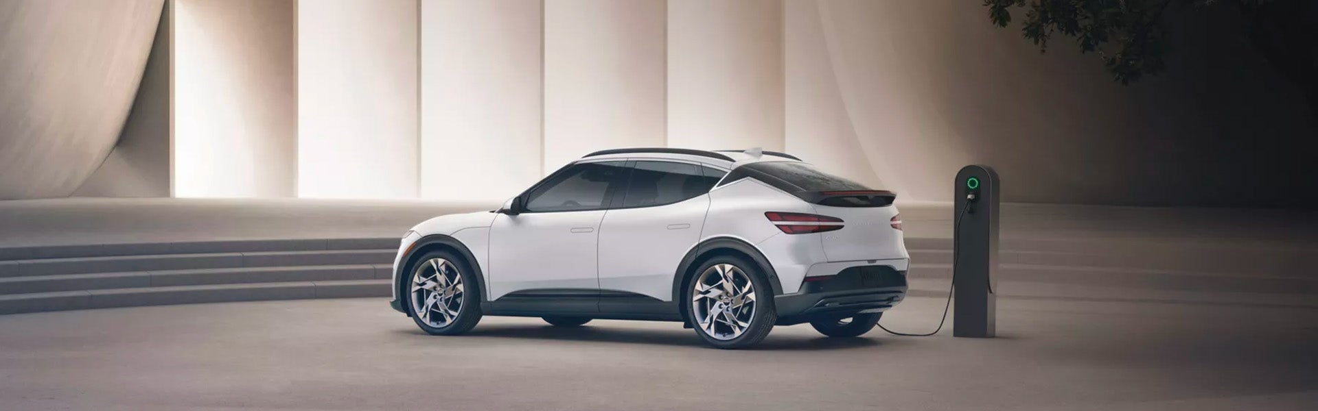 A Genesis GV60 electric SUV charging at a station.