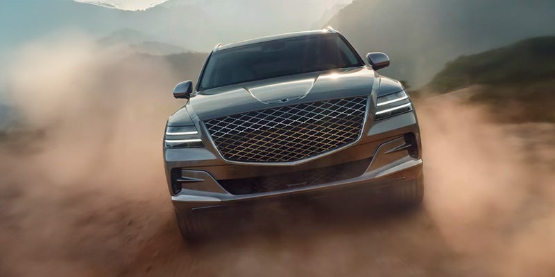 A modern SUV Genesis GV80 is moving forward in desert road.