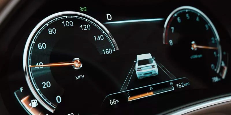 A modern car dashboard display showing a digital speedometer, fuel gauge, and a representation of a car ahead with MPG and temperature readings.