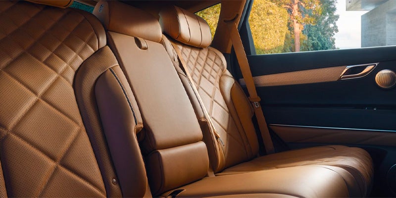 Interior view of a Genesis GV80's back seat, featuring brown leather upholstery with a quilted pattern.