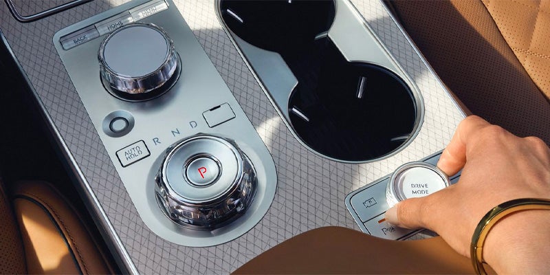 Hand adjusting drive mode on a car center console.